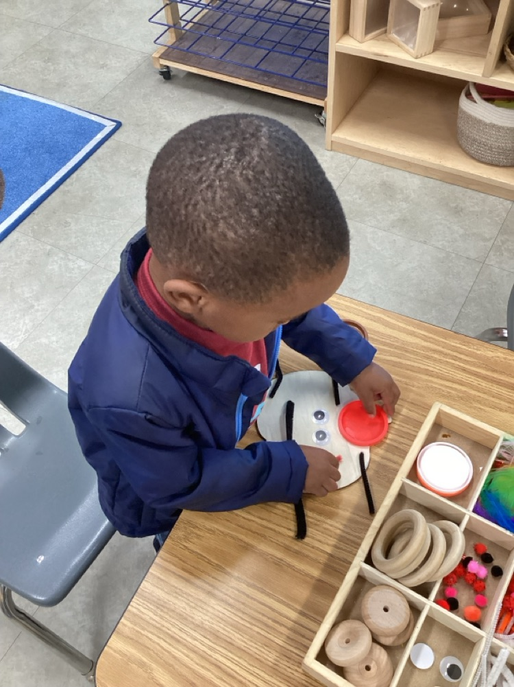 child using various loose parts to create a emotion face on a wood pumpkin