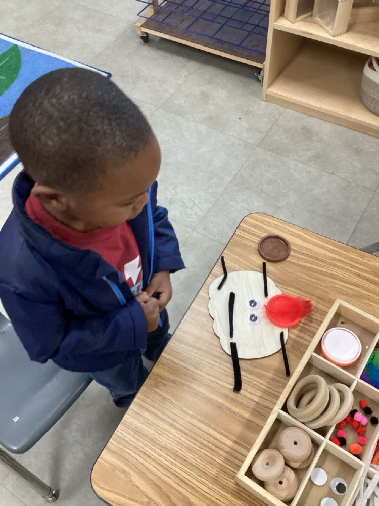 child using various loose parts to create a emotion face on a wooden pumpkin