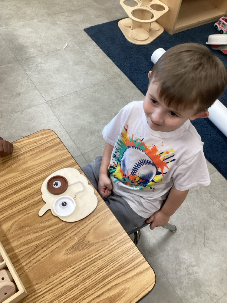 child created emotion face using loose parts on a wooden pumkin