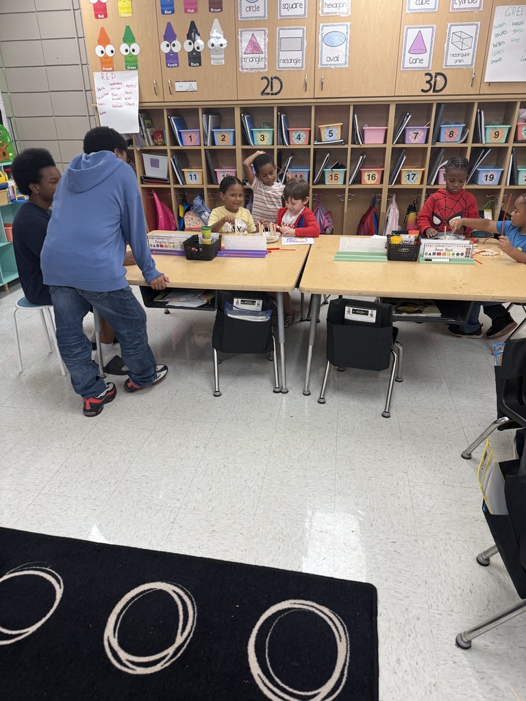 2 middle school students leaned over helping elementary students