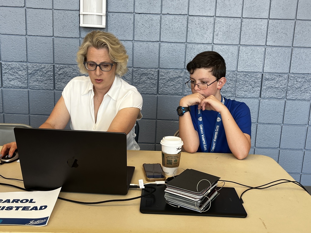 Student and adult sitting at a table working on a computer designing yearbook