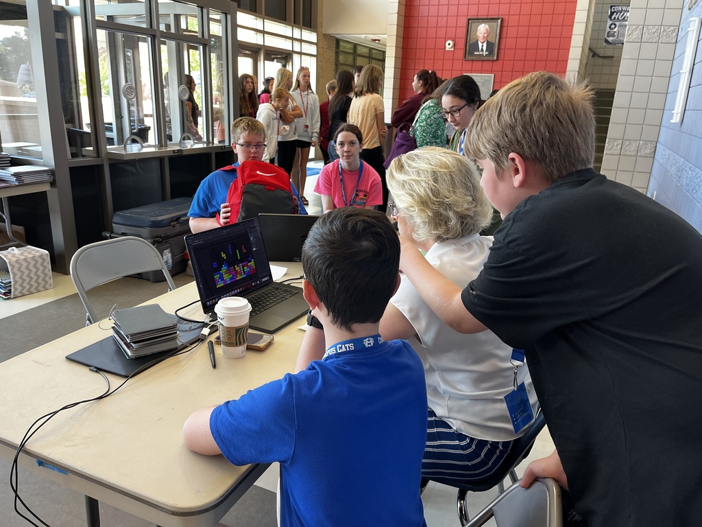Students and an adult gathered around a computer working on yearbooks