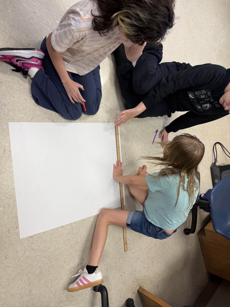 Students sitting in the floor drawing on large sheets of paper, creating their micro mansions