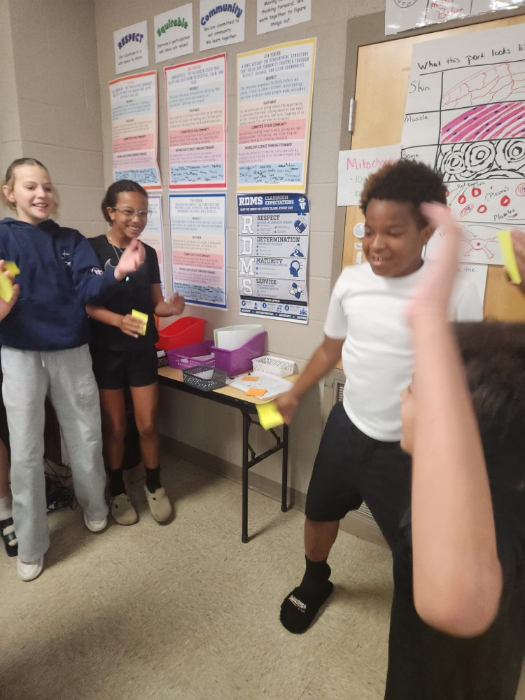 Two students doing Jumping Jacks at the Mitochondria station while two students look on smiling