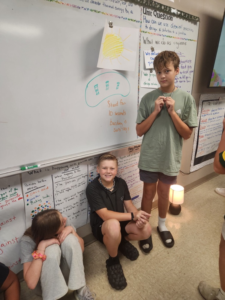 Students at the Chloroplast stage sitting next to lamps smiling while pretending to go through photosynthesis