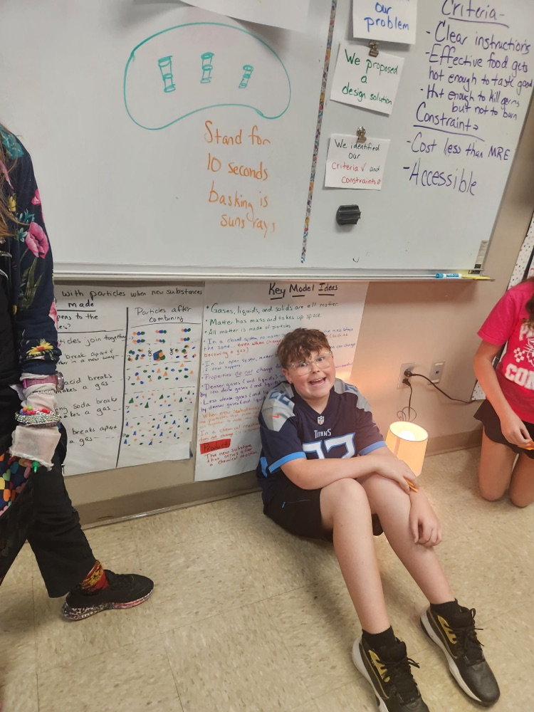 Students at the Chloroplast stage sitting next to lamps smiling while pretending to go through photosynthesis