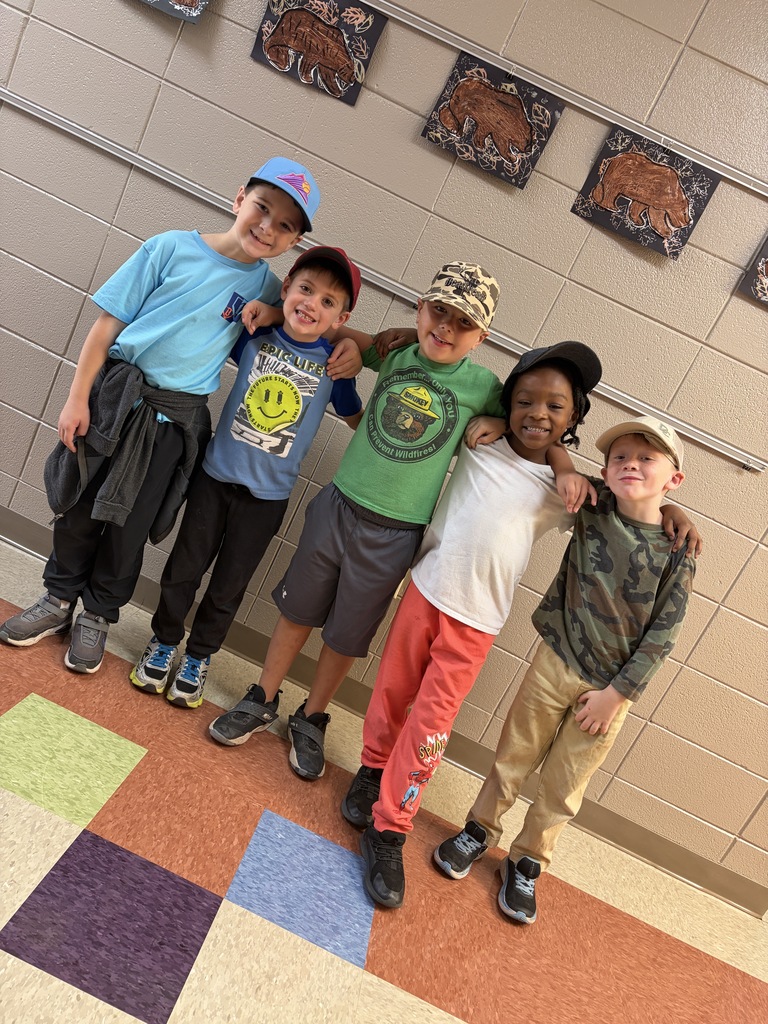 Five children pose for photo in a hallway with decorative wall hangings and multicolored floor.