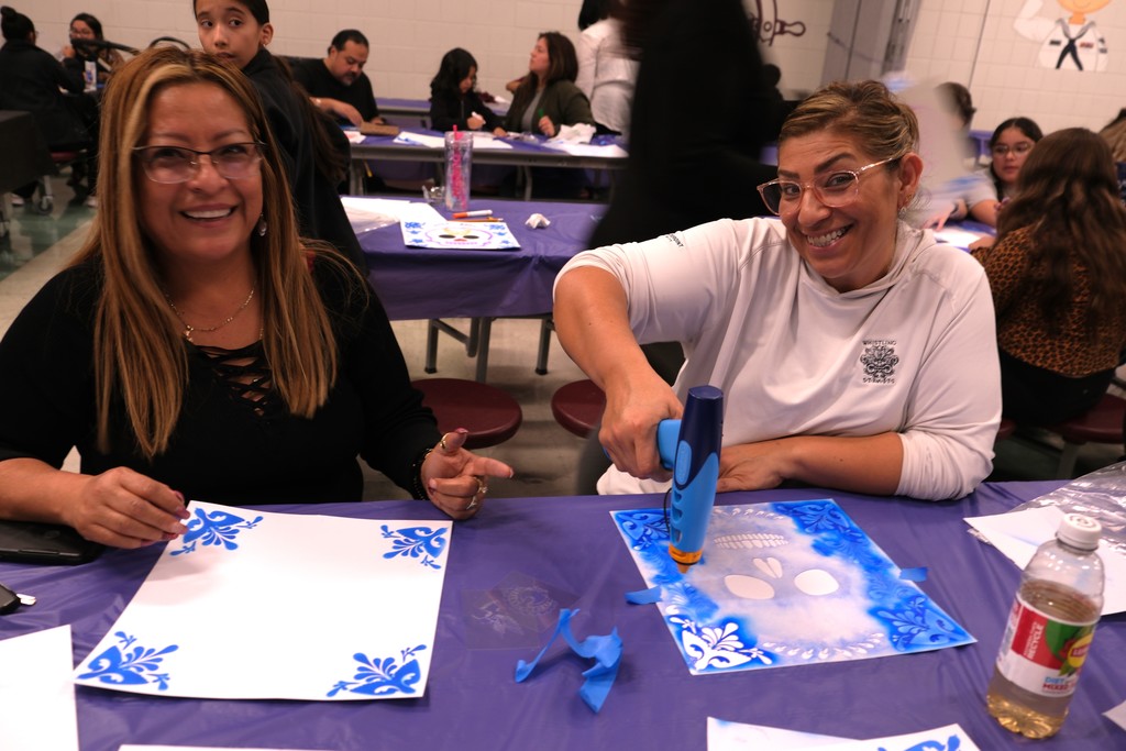 two women creating a skull craft, looking at camera