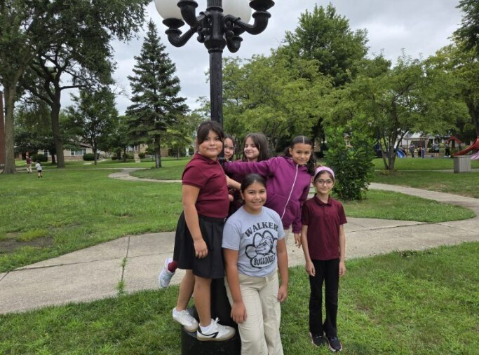 A cheerful group of girls poses under a street light, capturing a moment together in the morning