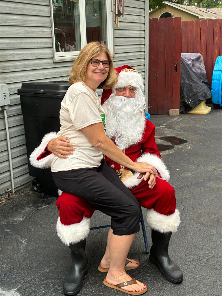A woman joyfully sitting on Santa Claus's lap, smiling and wearing a festive holiday outfit.