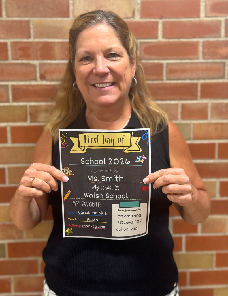 A woman holding a sign that says "First Day of School 2026" with her name, Ms. Smith, and the name of her school, Walsh School, along with a list of her favorite things.
