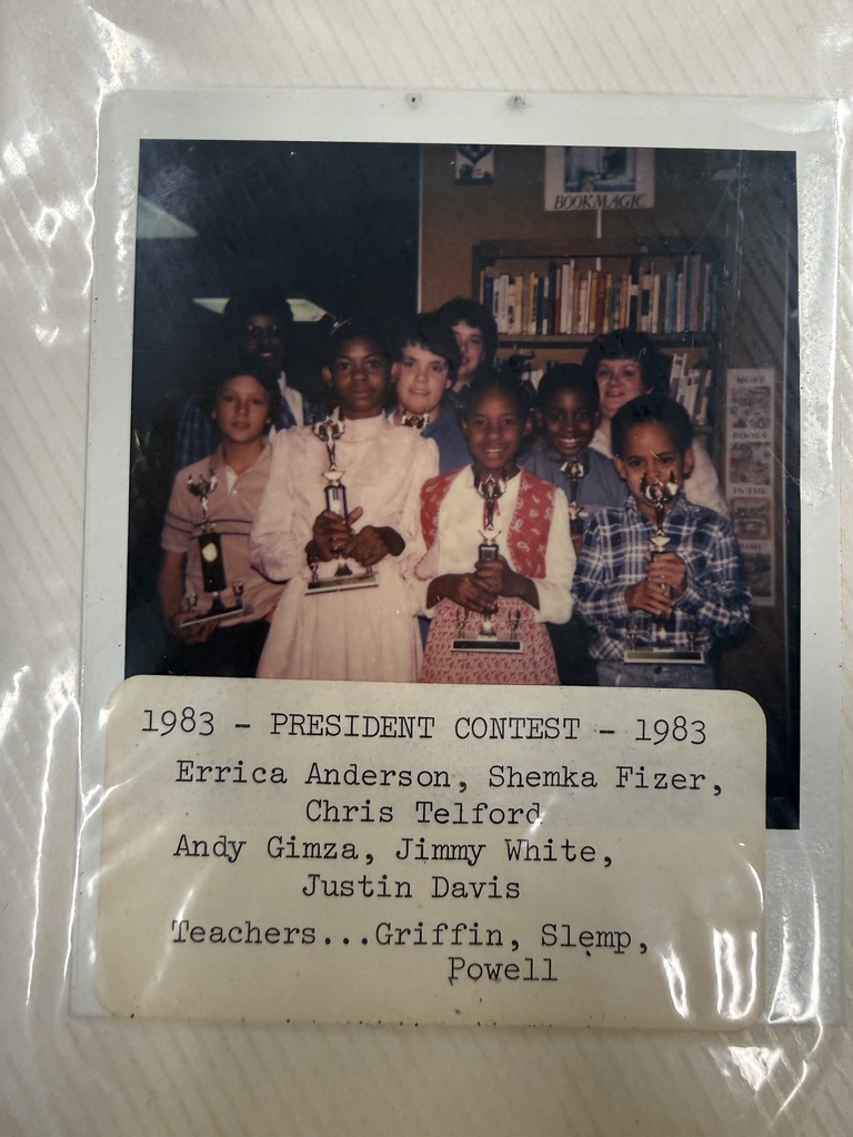 A faded 1983 school photo shows students holding trophies in a classroom; a caption lists a president contest and winners, with a proud, celebratory mood.