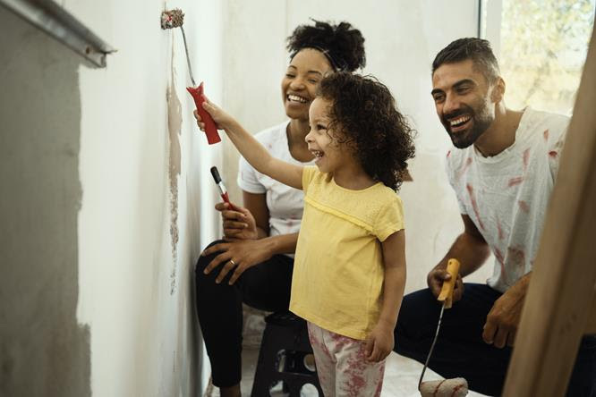 Family enjoying house painting together with rollers