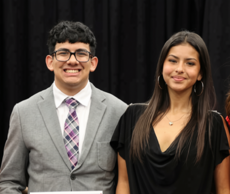2025-2026 KCBY Program Directors Aaron Montes and stand side by side holding certificates of commendation during an indoor recognition event.