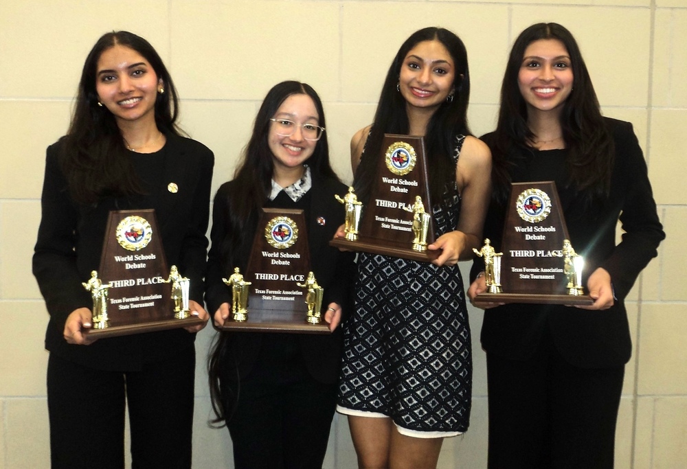  Four students stand side by side holding plaques that read “World Schools Debate, Third Place, Texas Forensic Association State Tournament