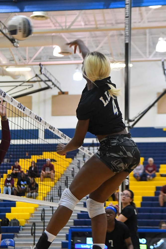 Volleyball player hitting ball above net