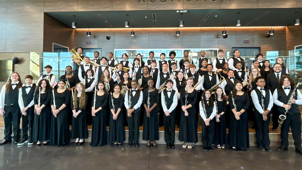 A group of band students smiling in an auditorium