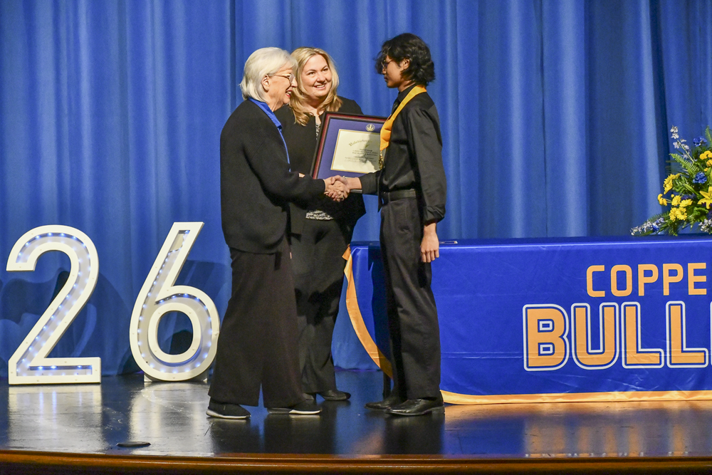 Student shaking hands with school board president on a stage