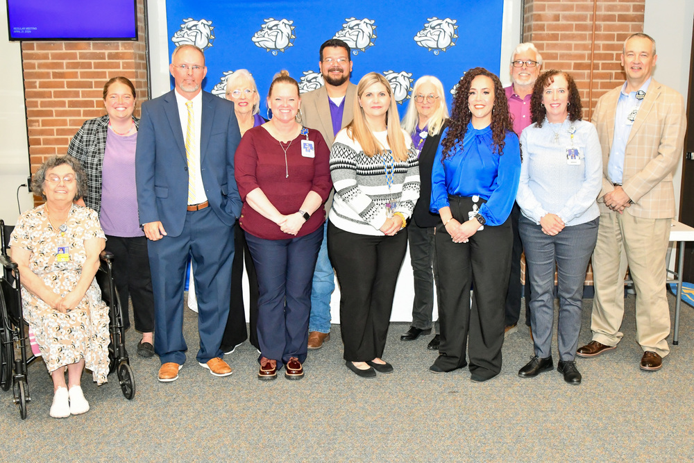 A group of people smiling in front of a backdrop