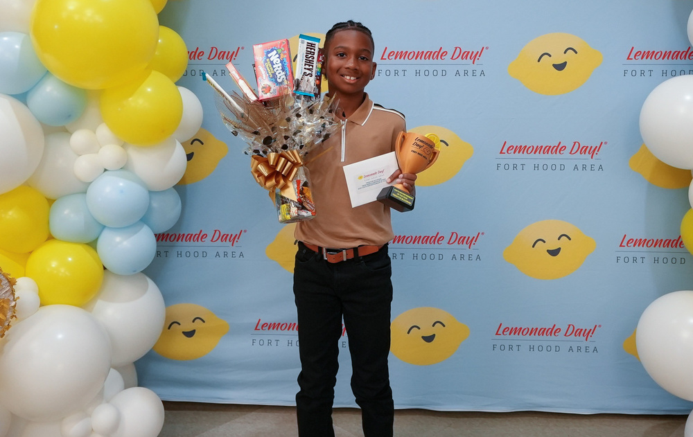 Trenton Buckram holding awards in front of a backdrop
