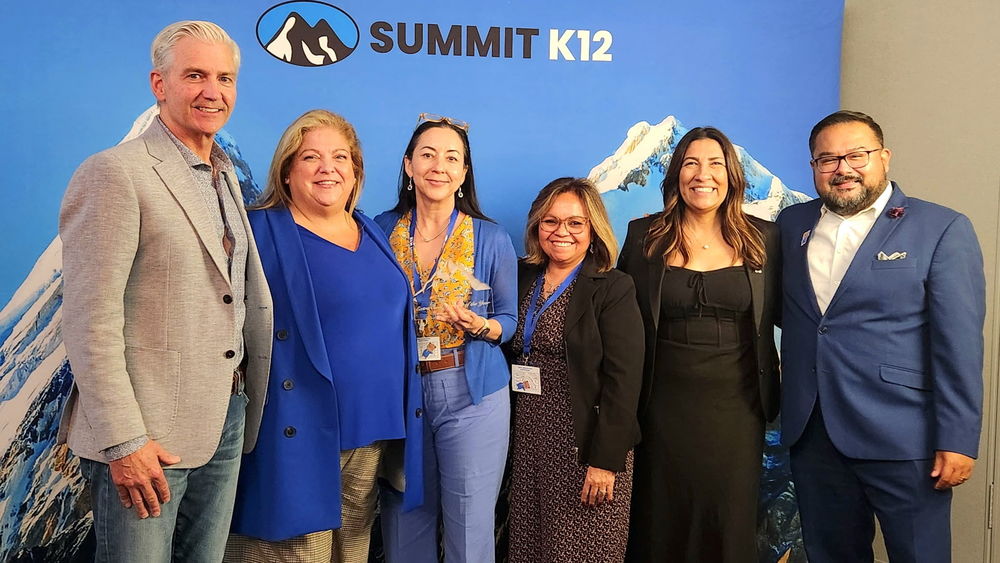 A group of people smiling holding an award