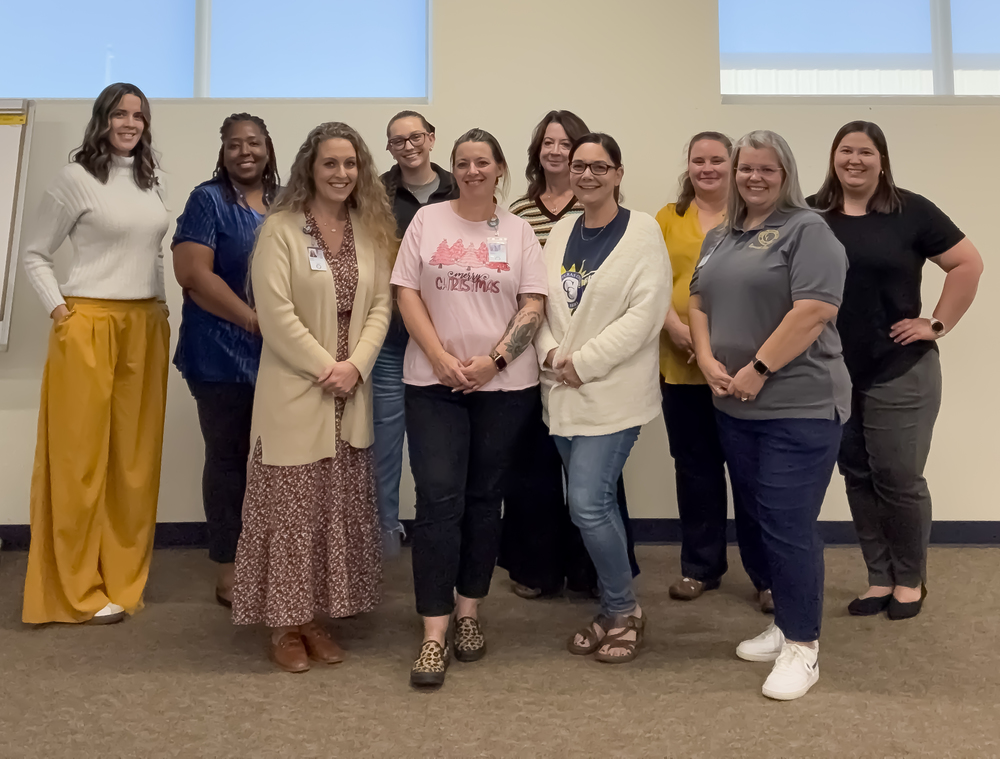 A group of women smiling in front of a wall