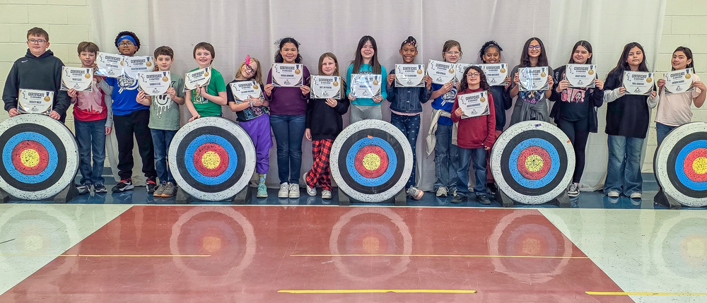 A group of archery students smiling for a photo