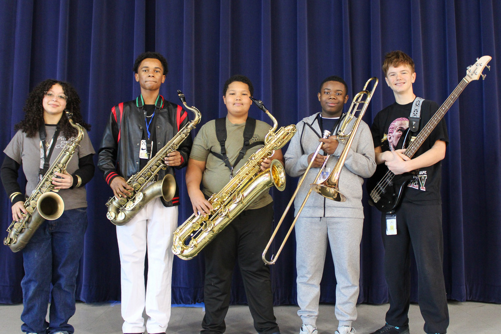 A group of five students holding instruments and smiling
