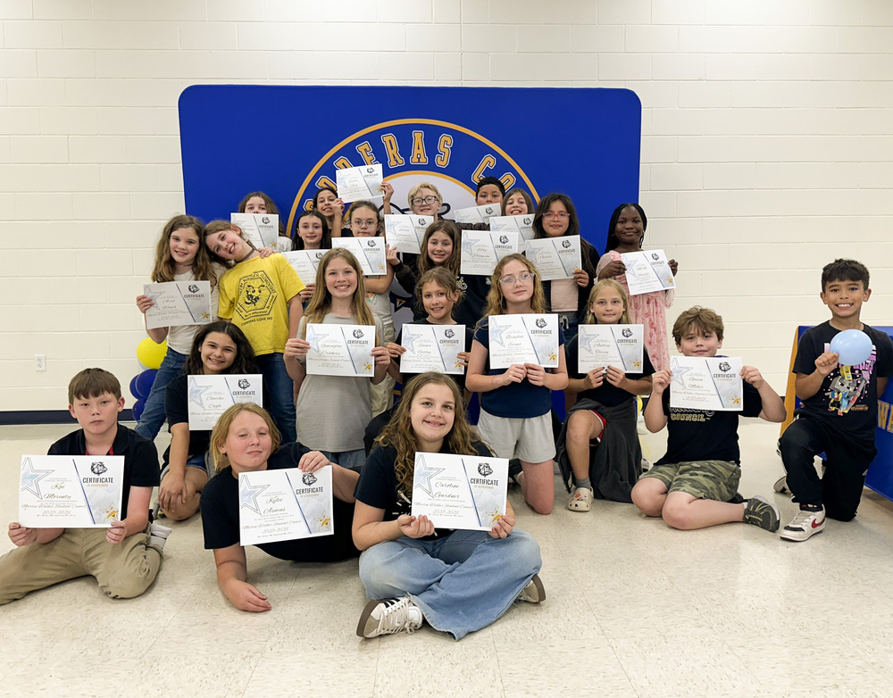 A group of smiling students holding certificates in front of a backdrop