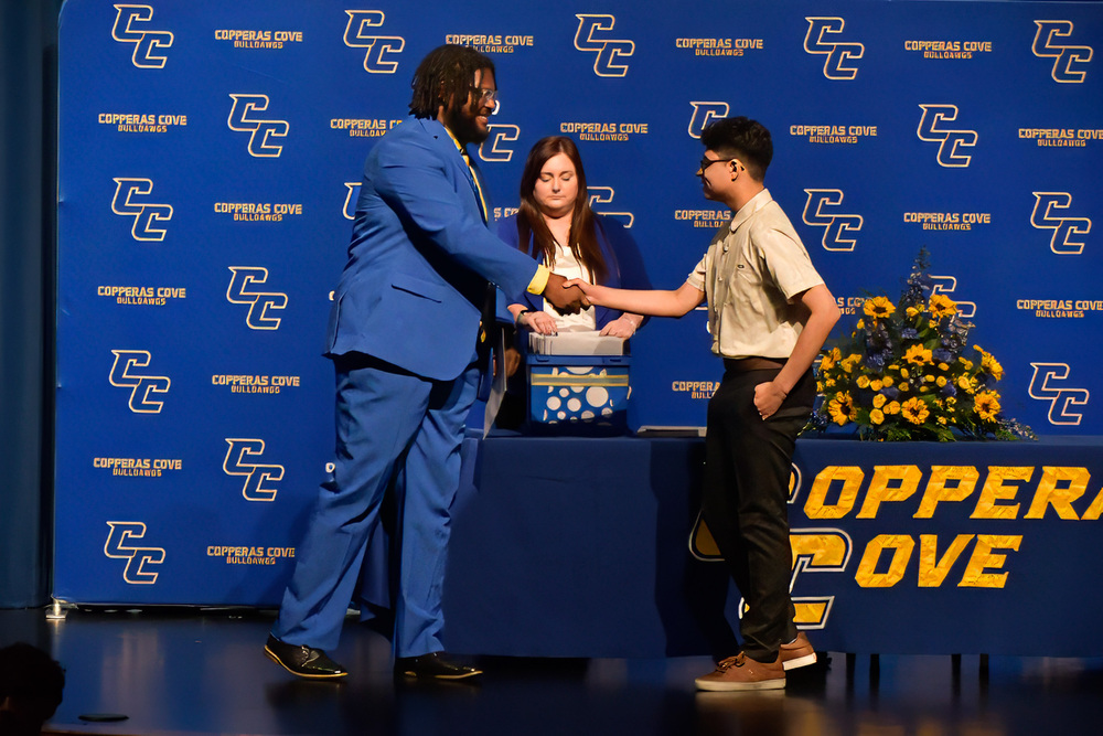 Administrator and student shaking hands with an award