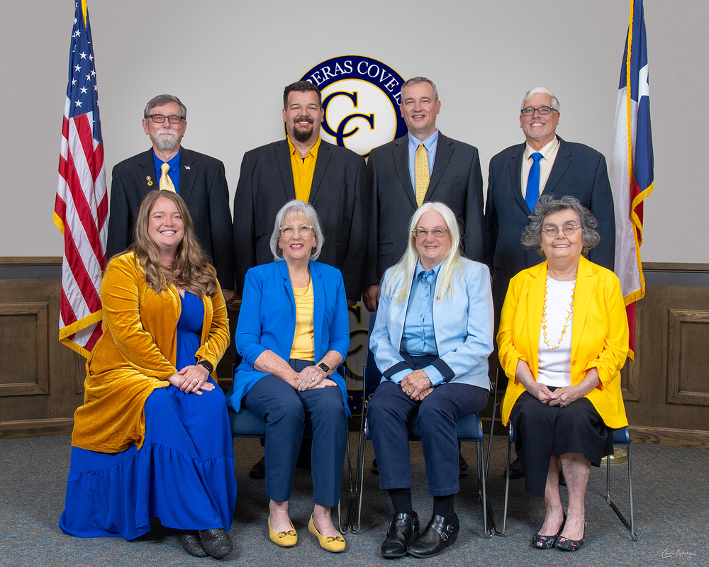 Group of smiling people in front of a dais and CCISD logo