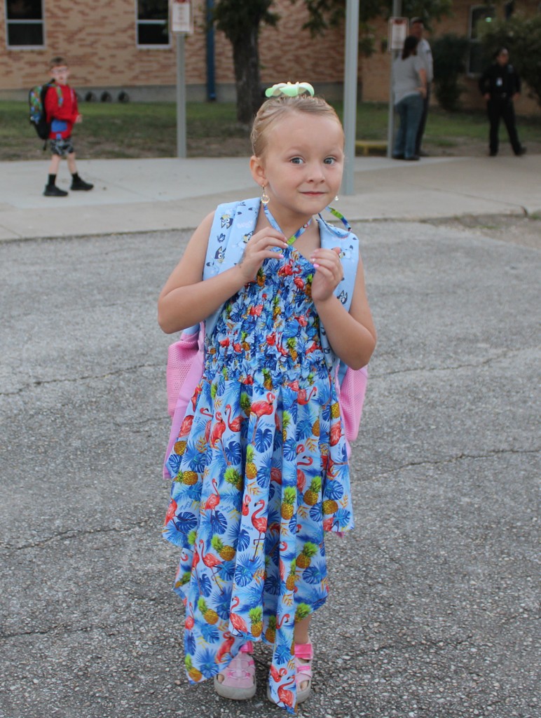 student in tropical dress poses outside school