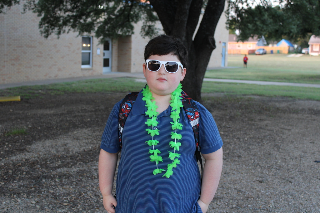 student in sunglasses and lei poses outside school