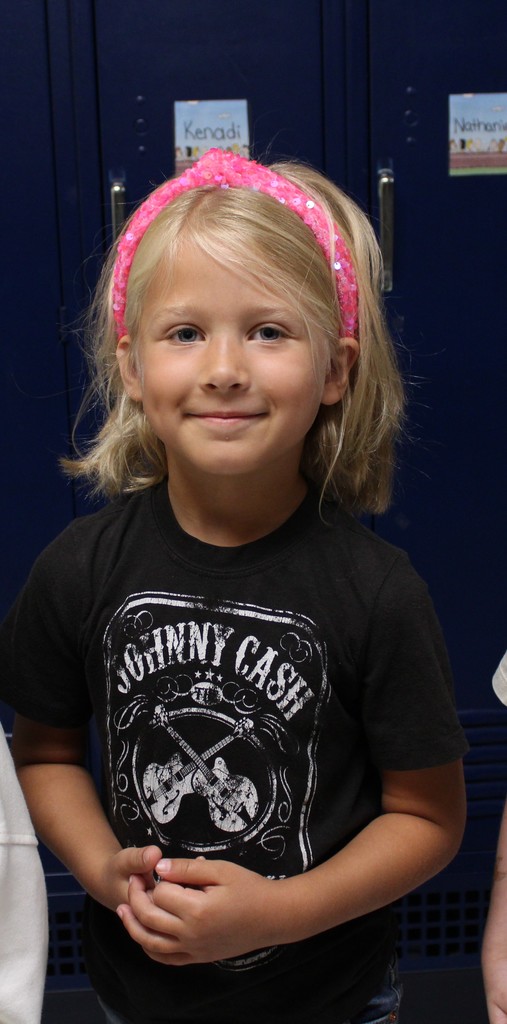 Student in band tee smiles in hallway