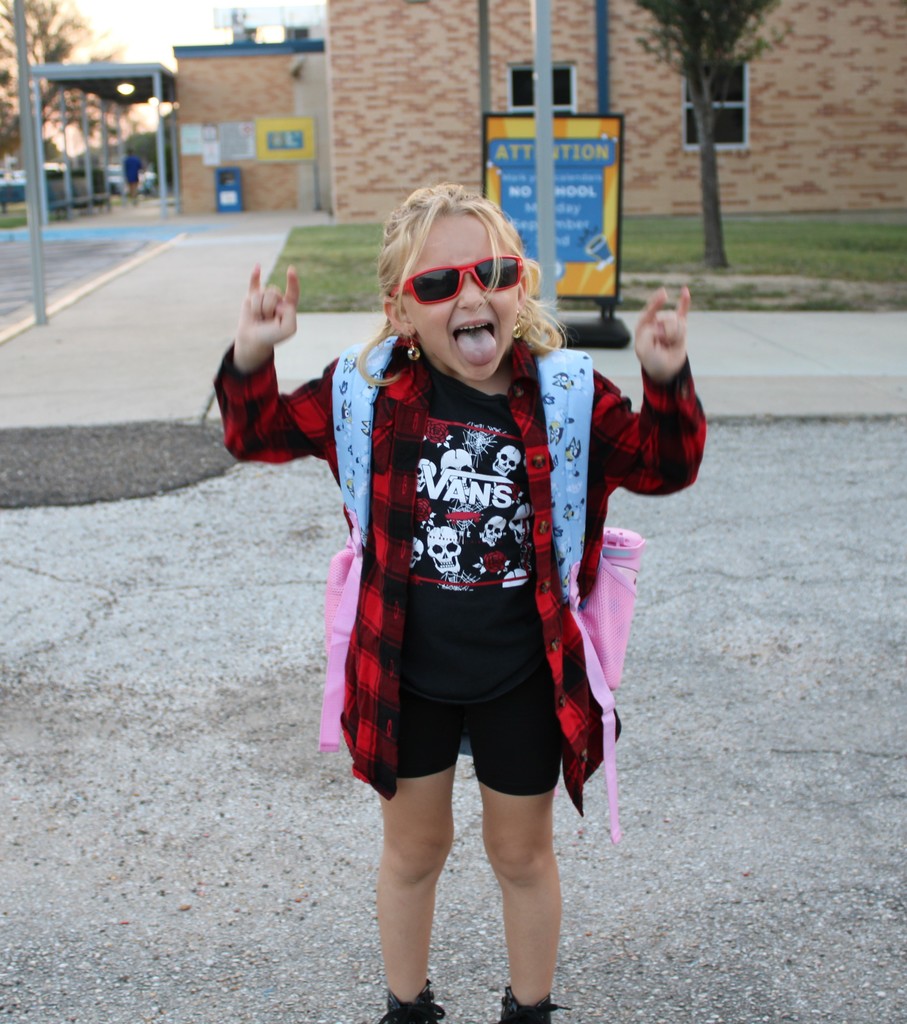 Student poses with tongue out in front of school