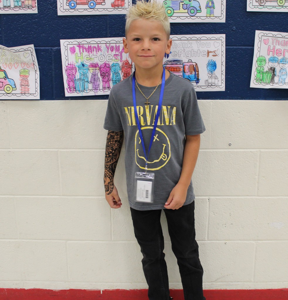 Student in band tee and fake tattoos poses in cafeteria.