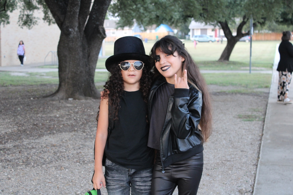 Two students dressed in rockstar costumes pose outside school