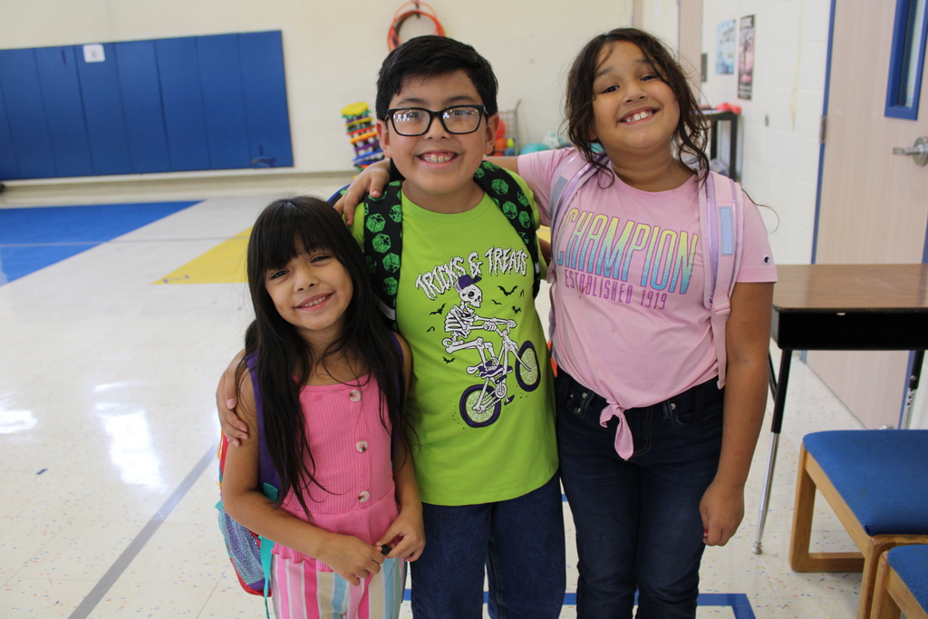 three students in neon clothes hug and smile in gym