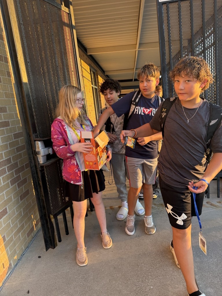 Picture of students greeting arriving to campus students with a HELLO and snacks