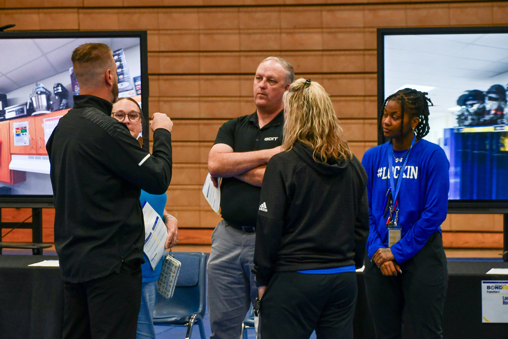 A group of adults talking near two screens