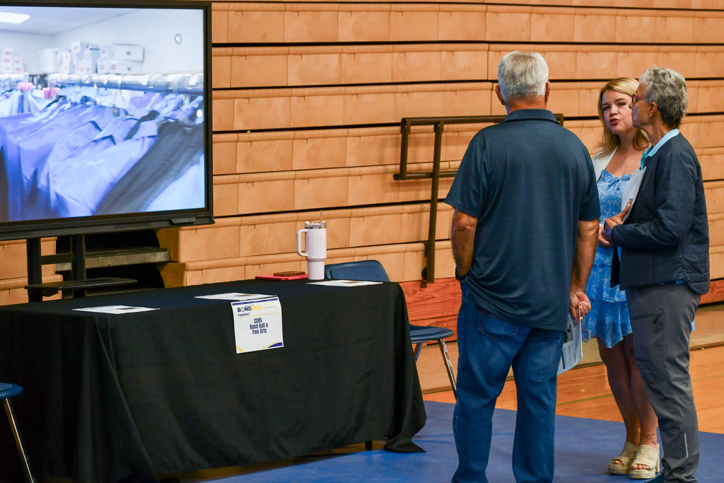 Three adults talking in front of a screen