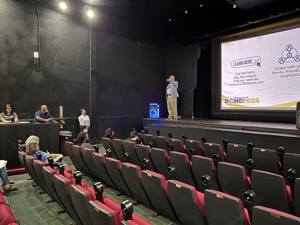 A man on a stage presenting in a theater
