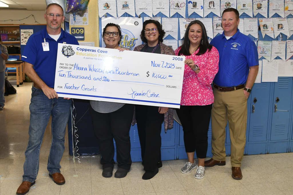 A group of people smiling holding a presentation check