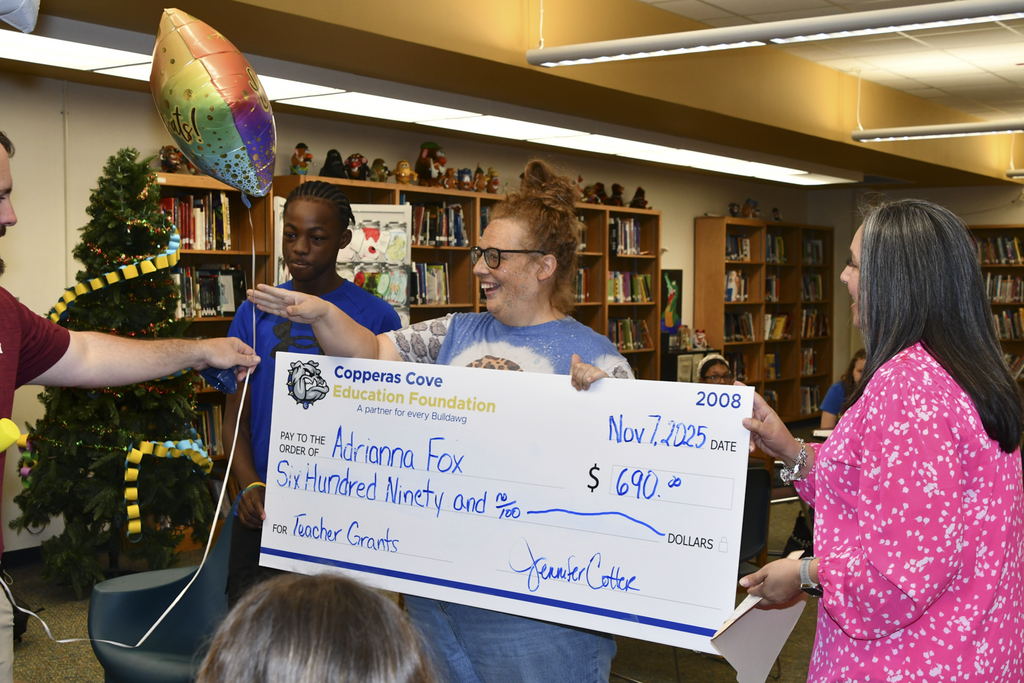 A group of people smiling holding a presentation check