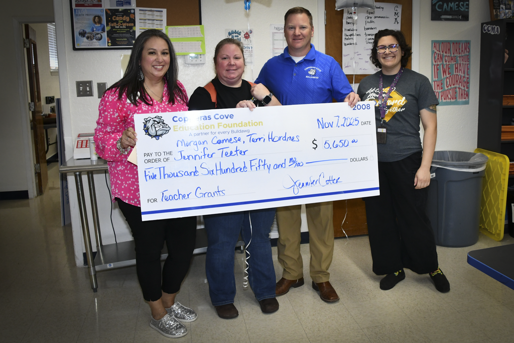 A group of people smiling holding a presentation check