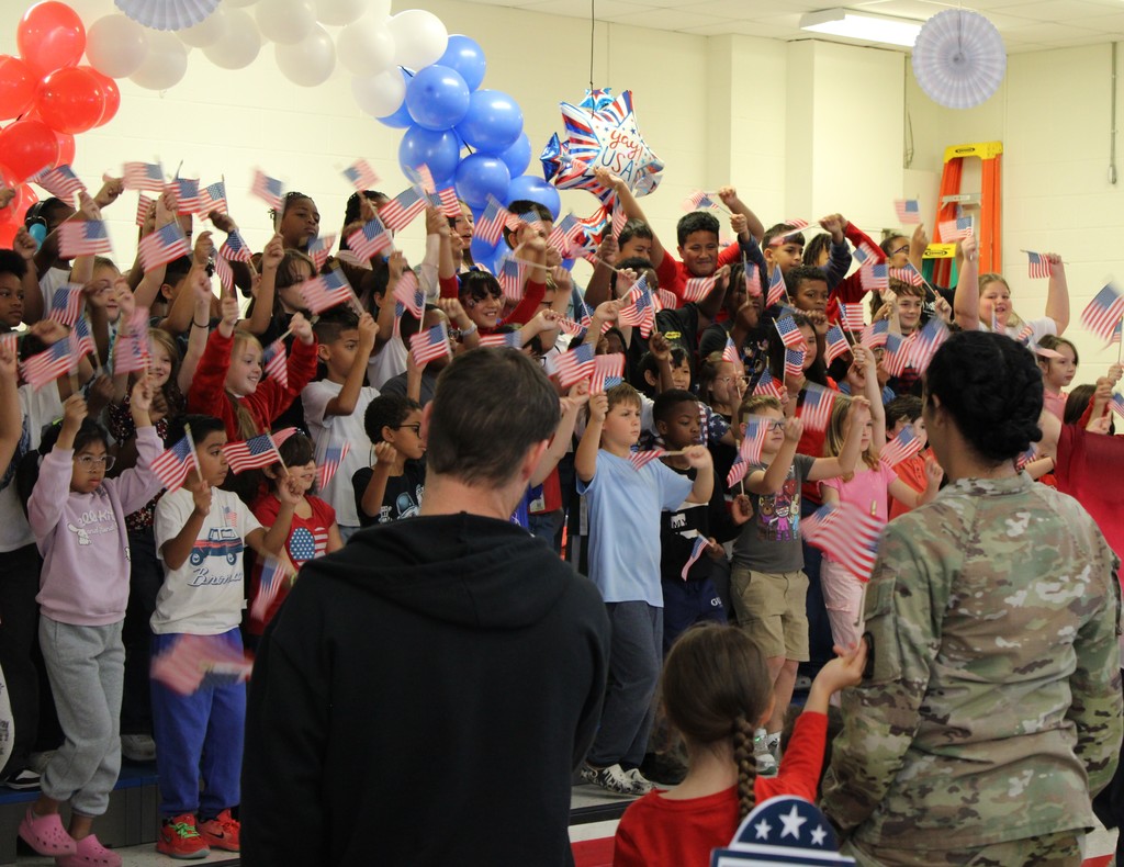 Students on stage wave American flags