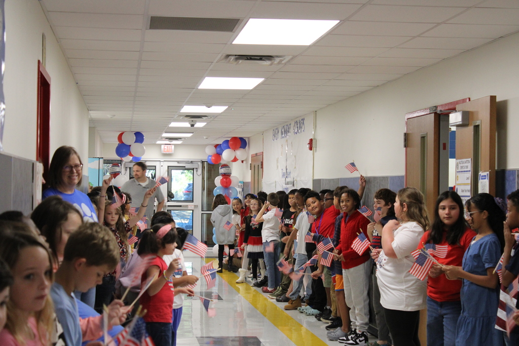 Students wait with flags to greet Veterans Parade