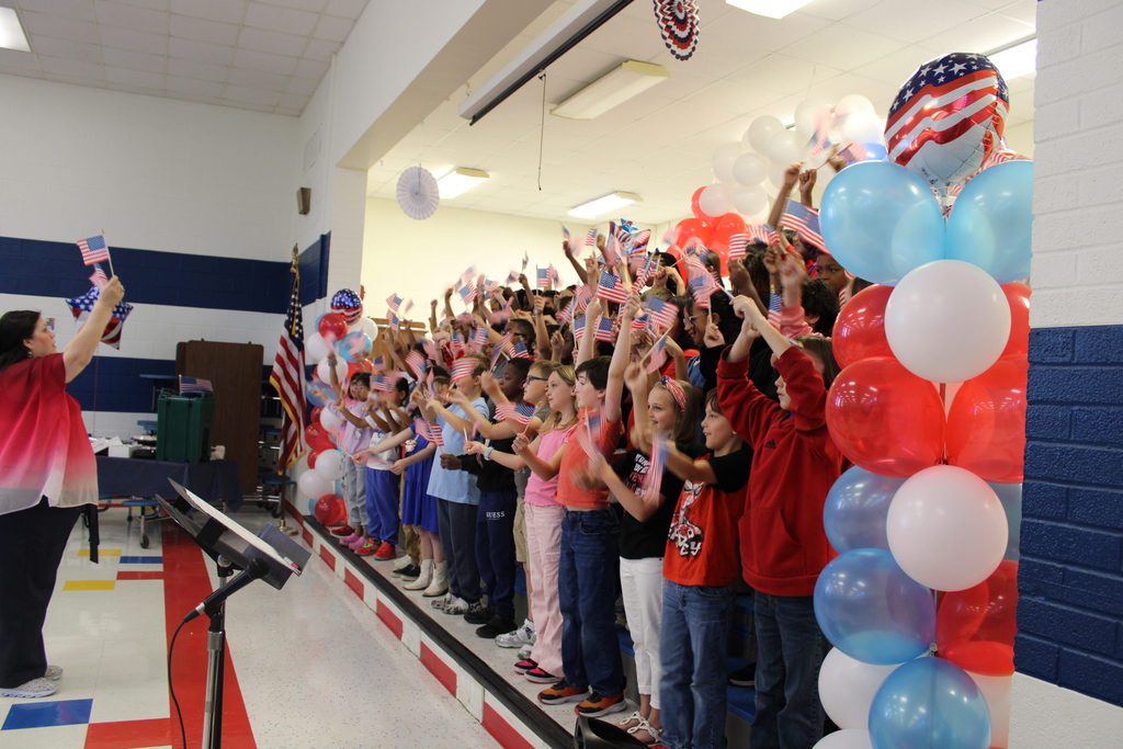 Students on stage wave American flags