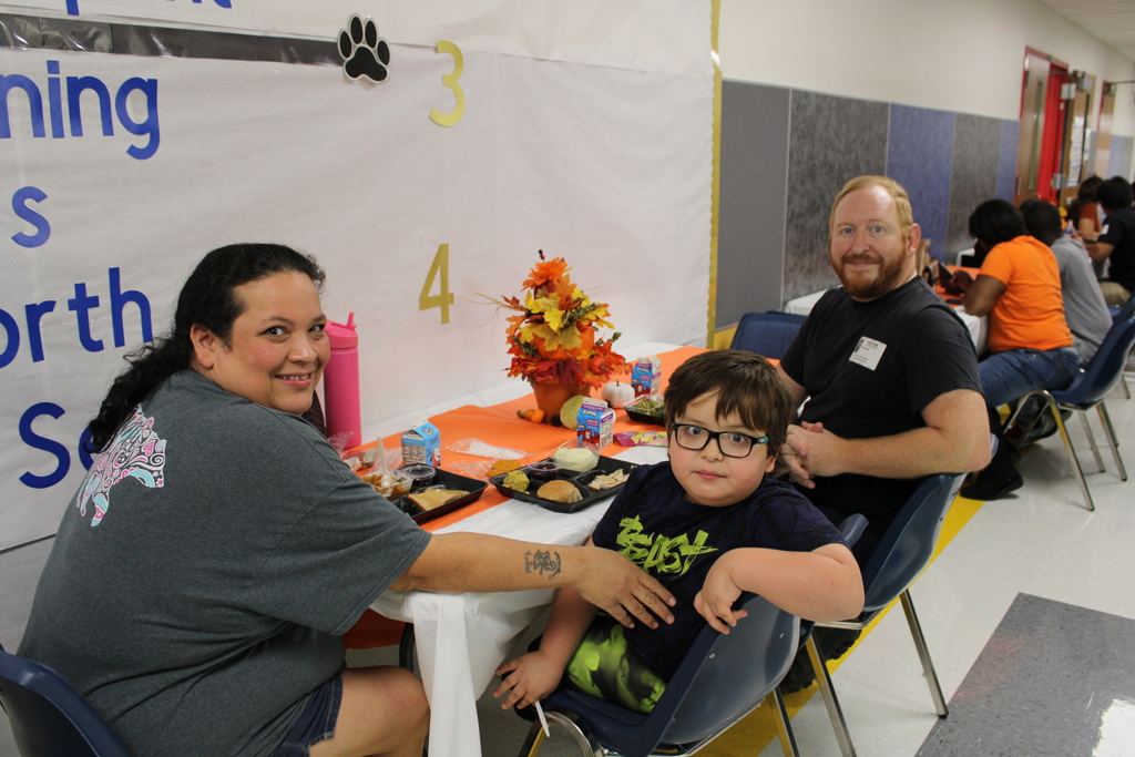 Student pose with parents for Thanksgiving feast