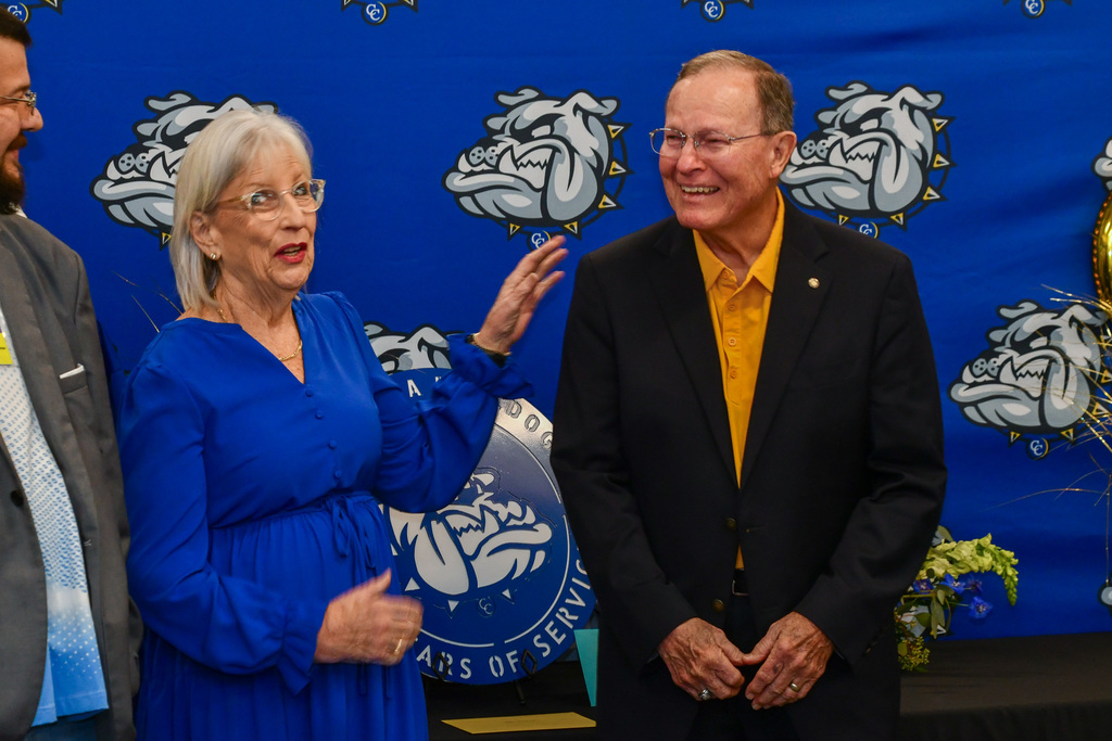 A woman and a man laughing in front of a backdrop
